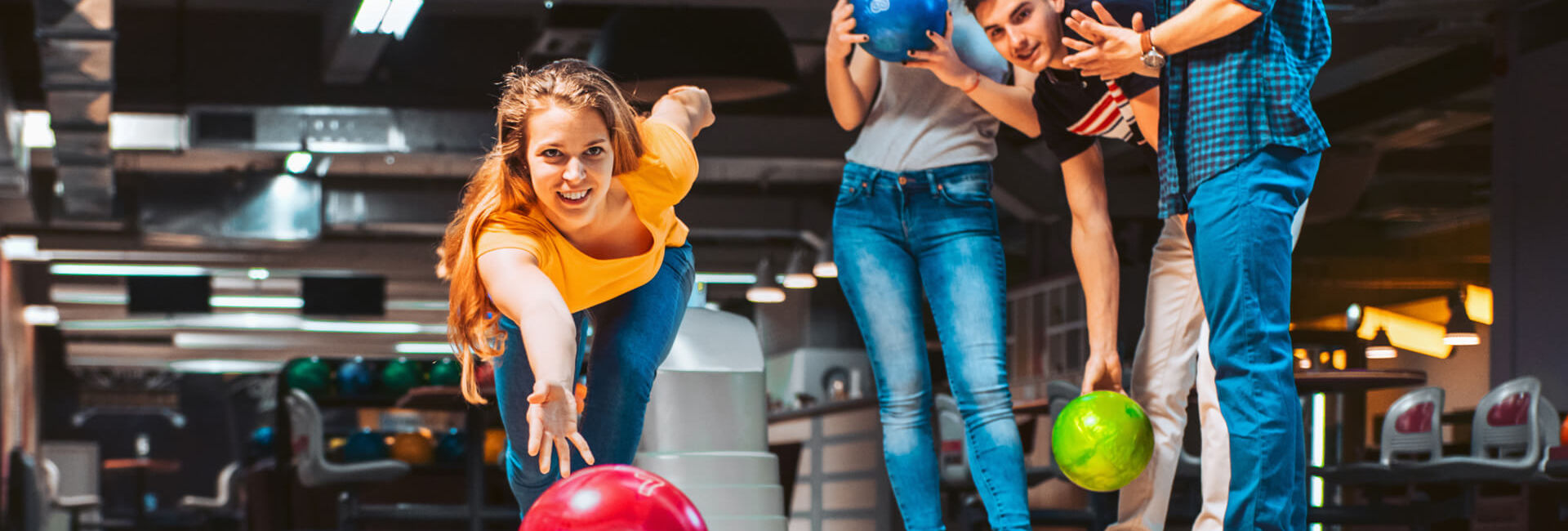 Young girl bowling with friends
