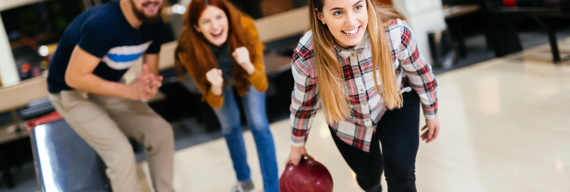 Female bowling while friends cheering