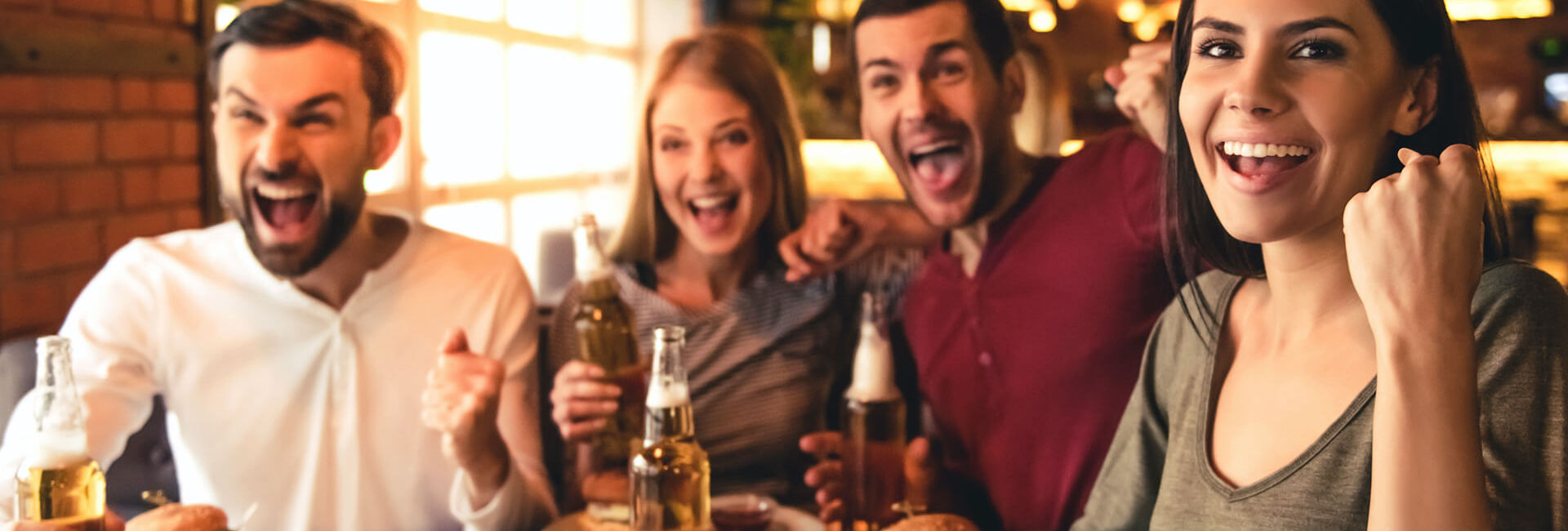 Twee vrouwen en twee mannen juichen en drinken bier - Pubquiz